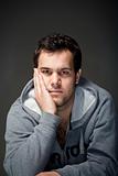 portrait of a young tough man with dark hair - isolated on dark gray
