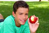 teenager eating red apple ongrass