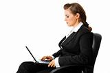 pensive modern business woman sitting on chair and using laptop
