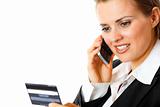 smiling modern business woman holding credit card and talking on mobile phone
