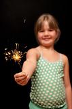 girl holding yellow sparkler firework with her hand and smiling