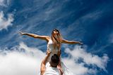 young couple dancing on sky background, freedom and relax symbol 