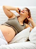 Laughing beautiful pregnant woman  relaxing on sofa and talking mobile phone.
