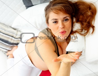 Lying on sofa happy beautiful pregnant woman  blowing kiss
