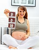 Smiling  beautiful pregnant  woman sitting on divan with echo in hand.
