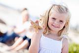 Adorable Little Blonde Girl with Starfish at The Beach.
