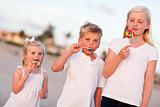 Cute Brother and Sisters Enjoying Their Lollipops at the Beach.