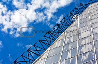 Glass wall of a greenhouse against blue sky and clouds