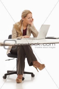 Young business girl sitting at desk with laptop