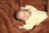 Newborn baby sleeping in soft brown blanket