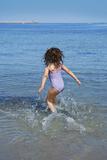 brunette little girl running into beach water