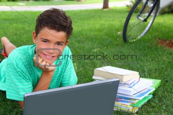 boy teenager studying laying green grass garden