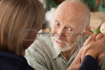 Senior couple at home holding hands focusing on man