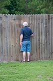 Adult Man Peeking Through a Hole in the Fence