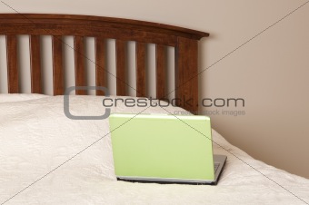 Working from home in a neutral colored bedroom on your bright green laptop computer.