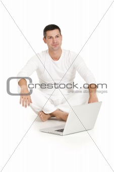 man dressed in white sitting on the floor with laptop