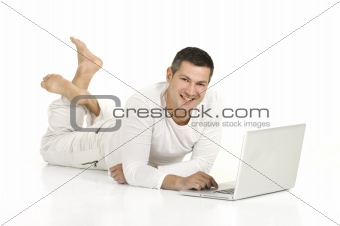 man dressed in white lying on the floor with laptop