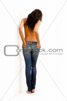 Back view of young woman with bare top wearing worn jeans