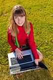 Beautiful girl with a laptop on the grass