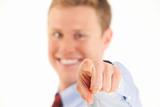 Portrait of smiling young businessman pointing finger at camera