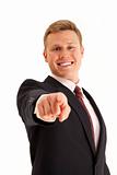 Portrait of smiling young businessman pointing finger at camera