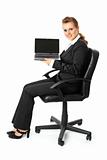 Smiling modern business woman sitting on  chair and holding laptop in hand with blank screen
