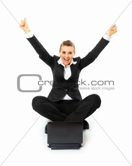 Excited modern business woman sitting on  floor and working on laptop 
