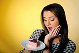 young beautiful girl eating small sweet cake. yellow background