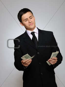 Young handsome business man in black suit and tie counting money