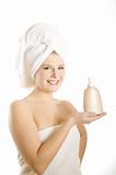 Young beautiful woman with healthy pure skin and white towel on her head holding moisturising cream in bathroom