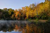 Morning mist on lake with trees turning autumn colors