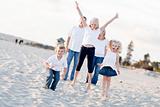 Happy Sibling Children Jumping for Joy at the Beach as Parents Watch.