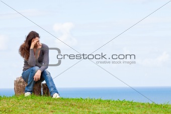 Depressed, sad and upset young woman sitting outside