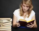 Young woman reads book against dark background