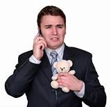 Young Businessman Crying on Cell Phone, clutching Teddy Bear.