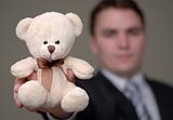 Businessman Shows Teddy Bear with Shallow Depth of Field