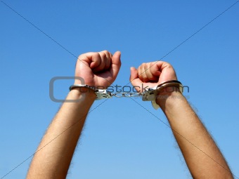 The hands of the men chained in handcuffs, on a background of th