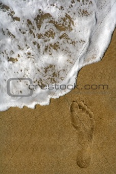 Footprint on sand and sea foam