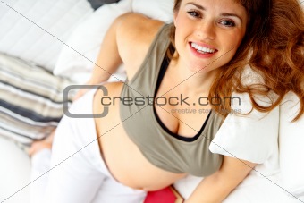 Smiling beautiful pregnant woman relaxing on sofa.
