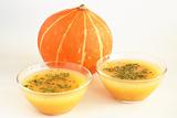 Two bowls of hot pumpkin soup and pumpkin on white background