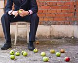 Businessman cleaning apples sitting on a stool