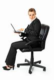 Displeased modern business woman sitting on chair and holding laptop in hand
