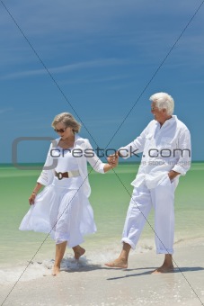 Happy Senior Couple Walking Holding Hands on A Tropical Beach
