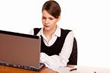 Young business woman sits on desk and works on laptop