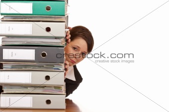 Frustrated business woman looks behind behind a folder stack