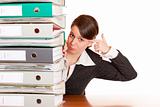 Frustrated business woman behind folder stack gets headshot