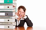 Frustrated business woman cries in office behind behind a folder stack