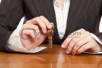 Business woman holds house key for handing over of keys
