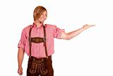 Happy man with oktoberfest leather trousers (lederhose) holds open hand for advertisement