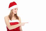 Smiling woman in Santa red hat pointing on blank space.